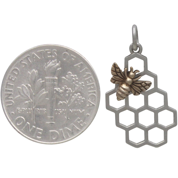 A U.S. dime is next to a Sterling Silver Honeycomb Charm with a Bronze Bee by Nina Designs, featuring an openwork honeycomb design and a gold-toned bee on top. The pendant matches the size of the dime.