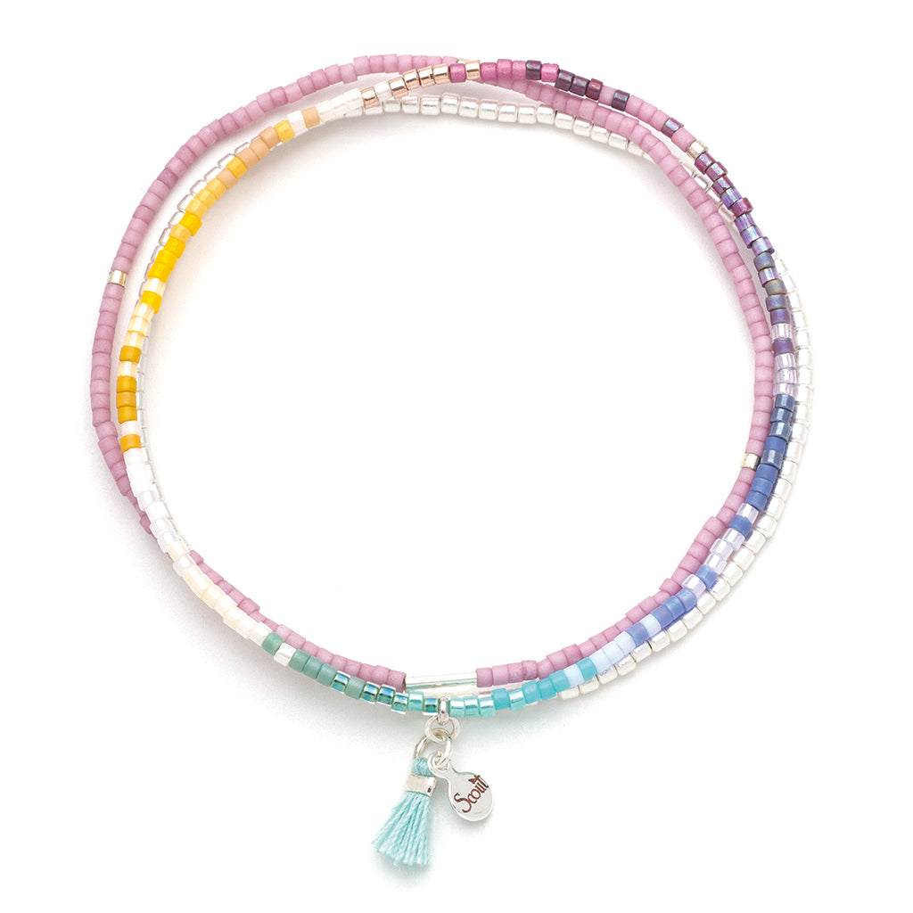 Introducing the Bright Multi Silver Miyuki Bracelet Trio by Scout Jewelry, a stunning accessory featuring pastel pink, yellow, white, blue, and purple beaded bracelets with the precision of Miyuki Delica craftsmanship. Each bracelet is adorned with a light blue tassel and a small round silver charm. Ideal for those who enjoy stacking bracelets to create vibrant circular arrangements.