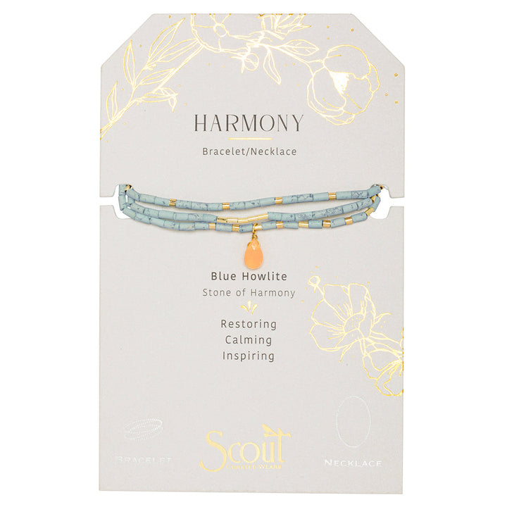 The "Harmony Blue Howlite Gold Teardrop Wrap" by Scout Jewelry features semi-precious stone beads in a bracelet/necklace, known for its restoring, calming, and inspiring properties. The packaging is elegantly embellished with delicate gold floral designs.