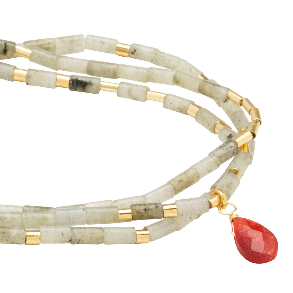 Introducing the Magic Labradorite Gold Teardrop Wrap by Scout Jewelry, featuring semi-precious stone beads in gray with gold-plated brass accents and a striking red teardrop pendant.