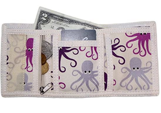 The Bungalow 360 Tri Fold Wallet Octopus, made from vegan canvas, opens to show compartments holding a two-dollar bill, coins, and a card. Its unique design features fun octopus patterns in shades of purple and gray set against a light background.