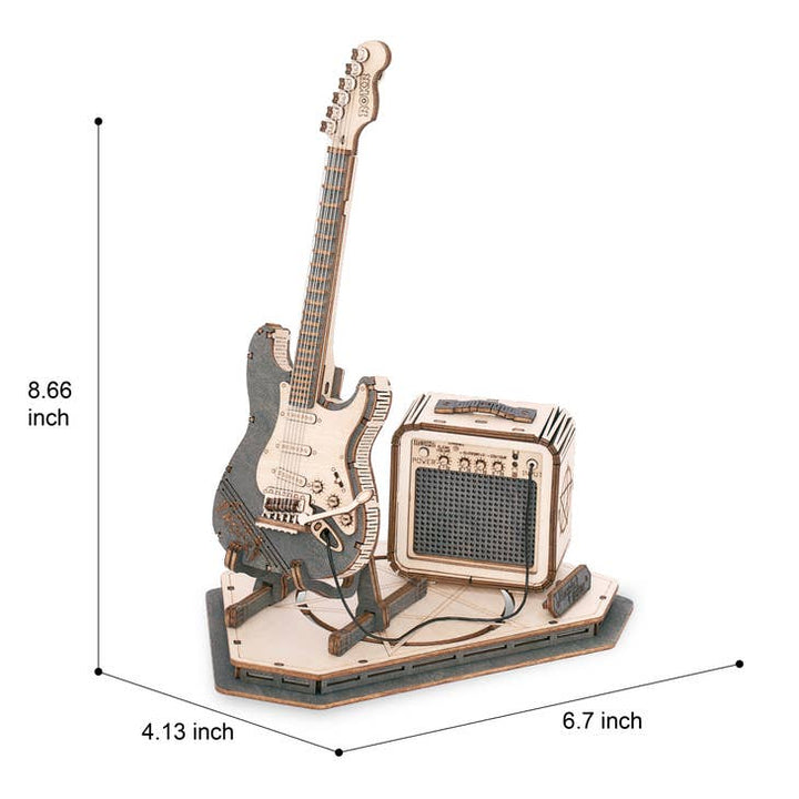 This Laser Cut Wooden Puzzle: Electric Guitar from Hands Craft is a detailed wooden model depicting an electric guitar and amplifier on a rectangular base. The amplifier features a textured speaker front, and the guitar leans against it. The dimensions of this intricate model are 8.66 inches tall, 6.7 inches wide, and 4.13 inches deep.