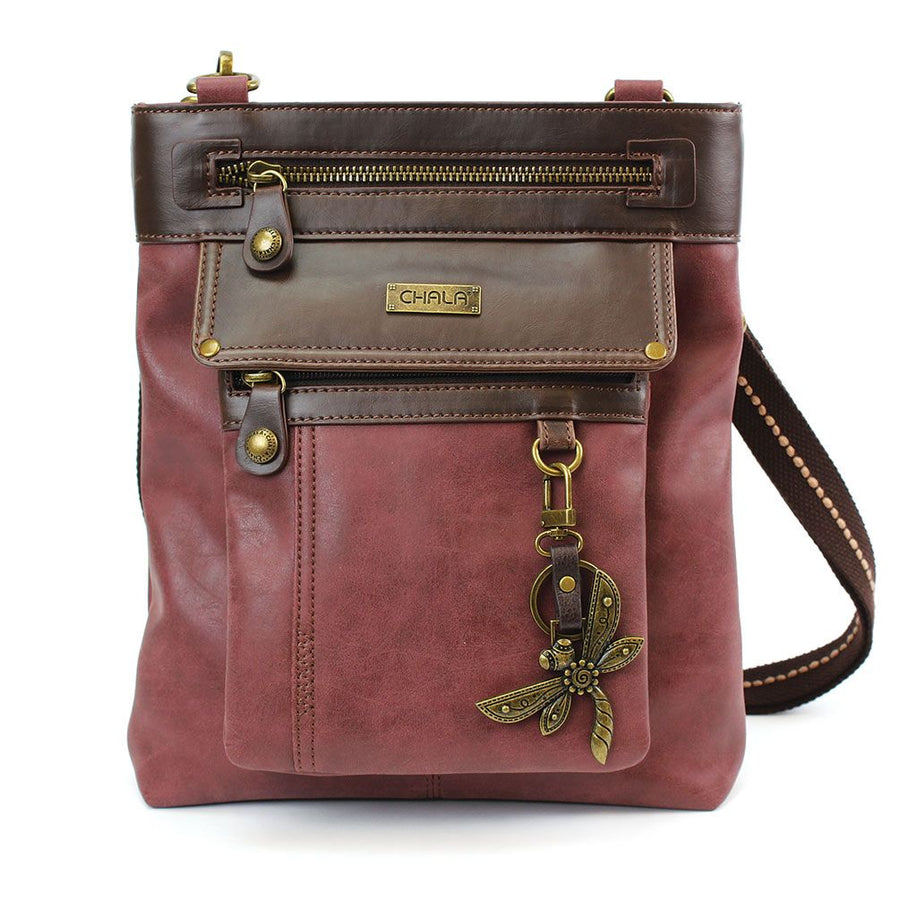 Introducing the Gemini Xbody w DF Burgundy by Chala, a chic two-tone purse made from high-quality faux leather in brown and reddish-brown. This bag includes a zippered pocket, decorative brass zippers, a distinctive brand plaque, and an enchanting dragonfly charm on the front. The adjustable strap in matching brown tone adds versatility to this multifunctional bag, perfect for any occasion.