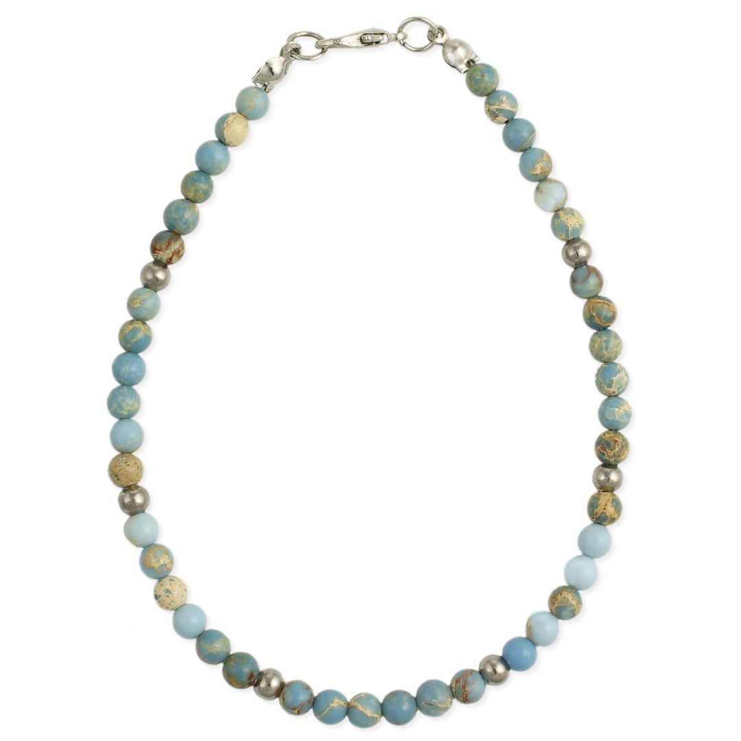 The Blue Jasper Bead Anklet by ZAD Jewelry features round beads in varying shades of light blue, white, and beige, some with speckled patterns and accented with imperial jasper. The beads are strung together with complementary silver plate beads and secured with a metal clasp at the top.