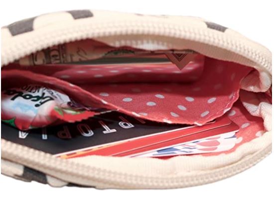 A close-up photo of an unzipped Tiny Wristlet Cat fabric pouch by Bungalow 360 with a light inner lining featuring white polka dots. Inside the pouch, various items are visible, including cards, perhaps credit or membership cards, and a packet of candy or gum. This vegan pouch showcases unique designs that appeal to mindful consumers.