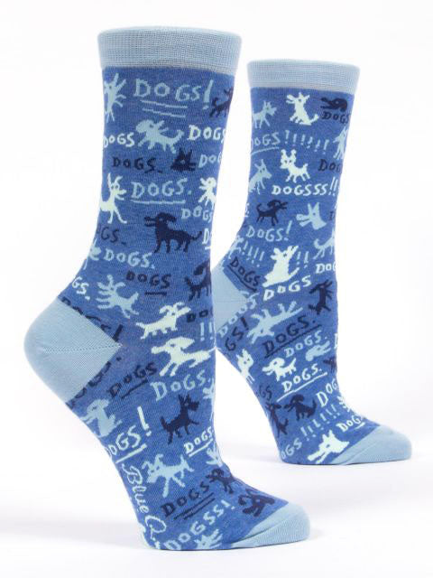 The Blue Q Dogs Dogs Socks are a pair of blue socks adorned with various dog silhouettes and the word "DOGS!!" in an array of fonts and shades of blue, white, and black. Crafted from combed cotton and spandex for extra comfort, these socks are designed to fit women's shoe sizes 5-10. They feature a light blue cuff, heel, and toe.