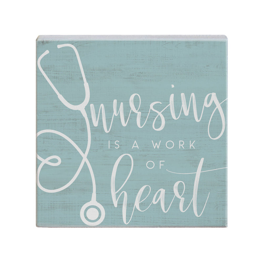 The Nursing Heart by SincereSurroundings is a handcrafted square sign in light teal, featuring the handwritten phrase "Nursing is a work of heart" in white. A stethoscope illustration creatively forms the letter "N." Display this heartfelt piece to honor nurses everywhere.