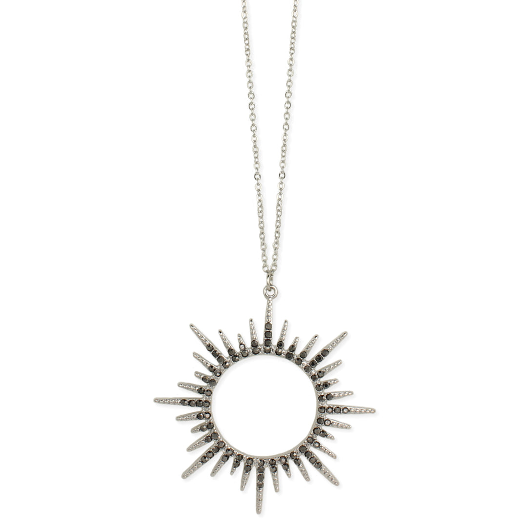 The Silver Sunburst Crystal Necklace from ZAD Jewelry features a fine link silver chain and a sunburst design pendant. The circular pendant has numerous rays extending outward, some adorned with small gray hematite crystals, giving it a radiant, spiked appearance.