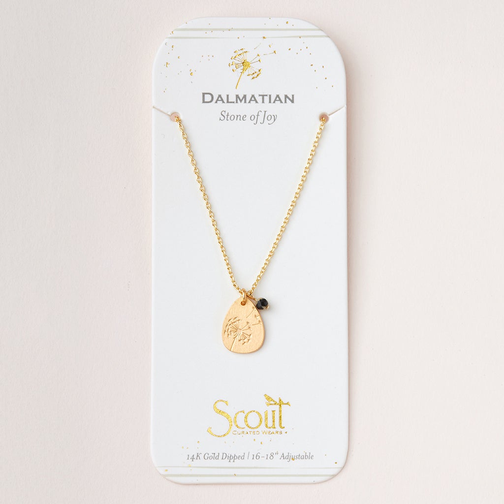 A gold necklace with an adjustable brass chain is shown on a card reading "Dalmatian Stone of Joy." It has icon charms, a small black bead, and the text "Scout Curated Wears, 14k Gold Dipped, 16-18'' Adjustable," matching Scout Jewelry's Intention Neck Labradorite/Gold.