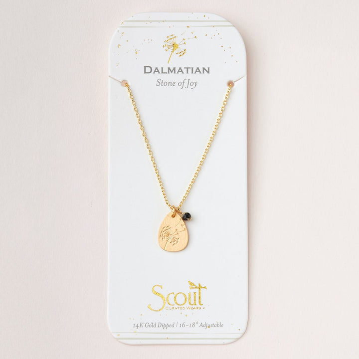 A gold necklace with an adjustable brass chain is shown on a card reading "Dalmatian Stone of Joy." It has icon charms, a small black bead, and the text "Scout Curated Wears, 14k Gold Dipped, 16-18'' Adjustable," matching Scout Jewelry's Intention Neck Labradorite/Gold.