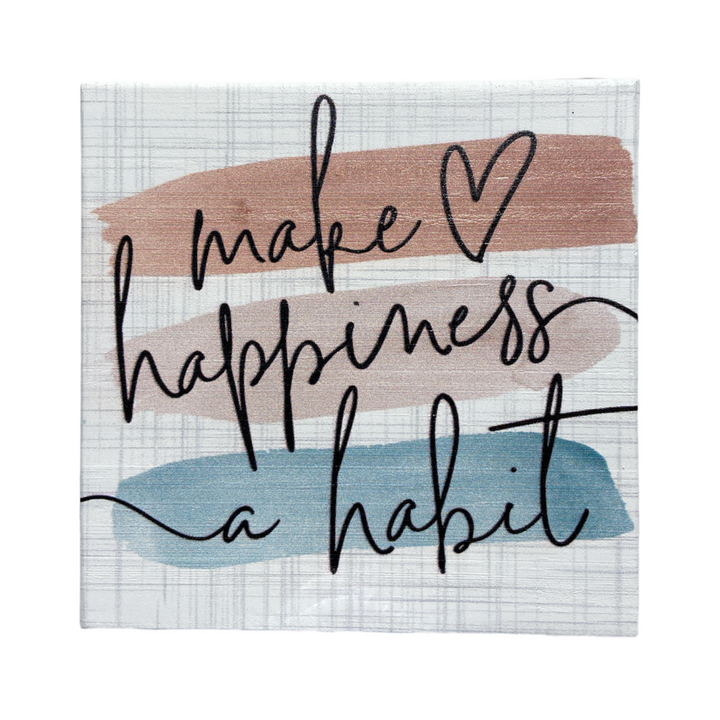 A handcrafted canvas from SincereSurroundings titled "Make Happiness" elegantly features the message "make happiness a habit" in black cursive over earthy tones of beige, brown, and blue. Ideal for a shelf display, the heart symbol replacing the dot in "i" adds charm to this piece originating from Rock Rapids, IA.