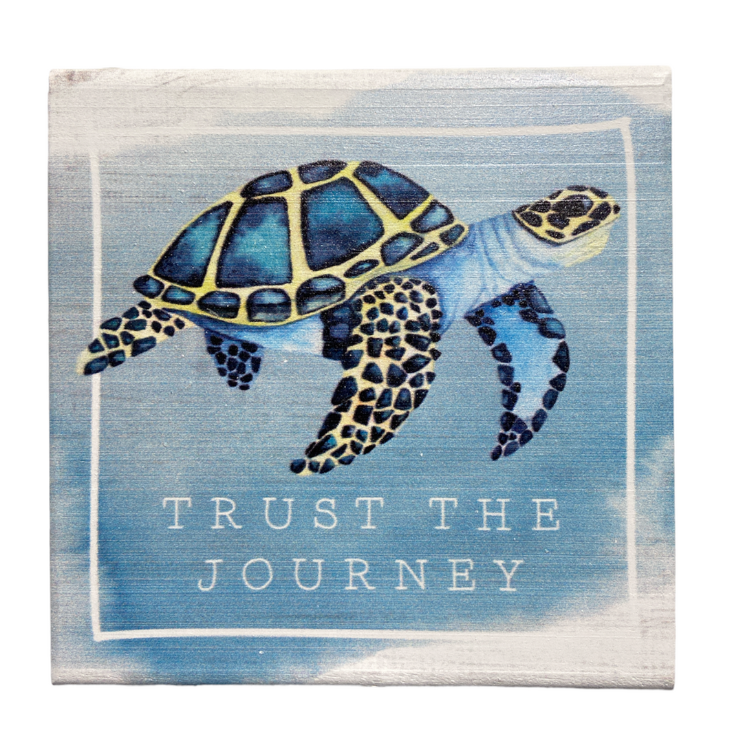 Featuring a handcrafted sea turtle swimming against a sky-like backdrop, the "Trust The Journey" design by SincereSurroundings is elegantly enclosed within a soft white square border for easy display.