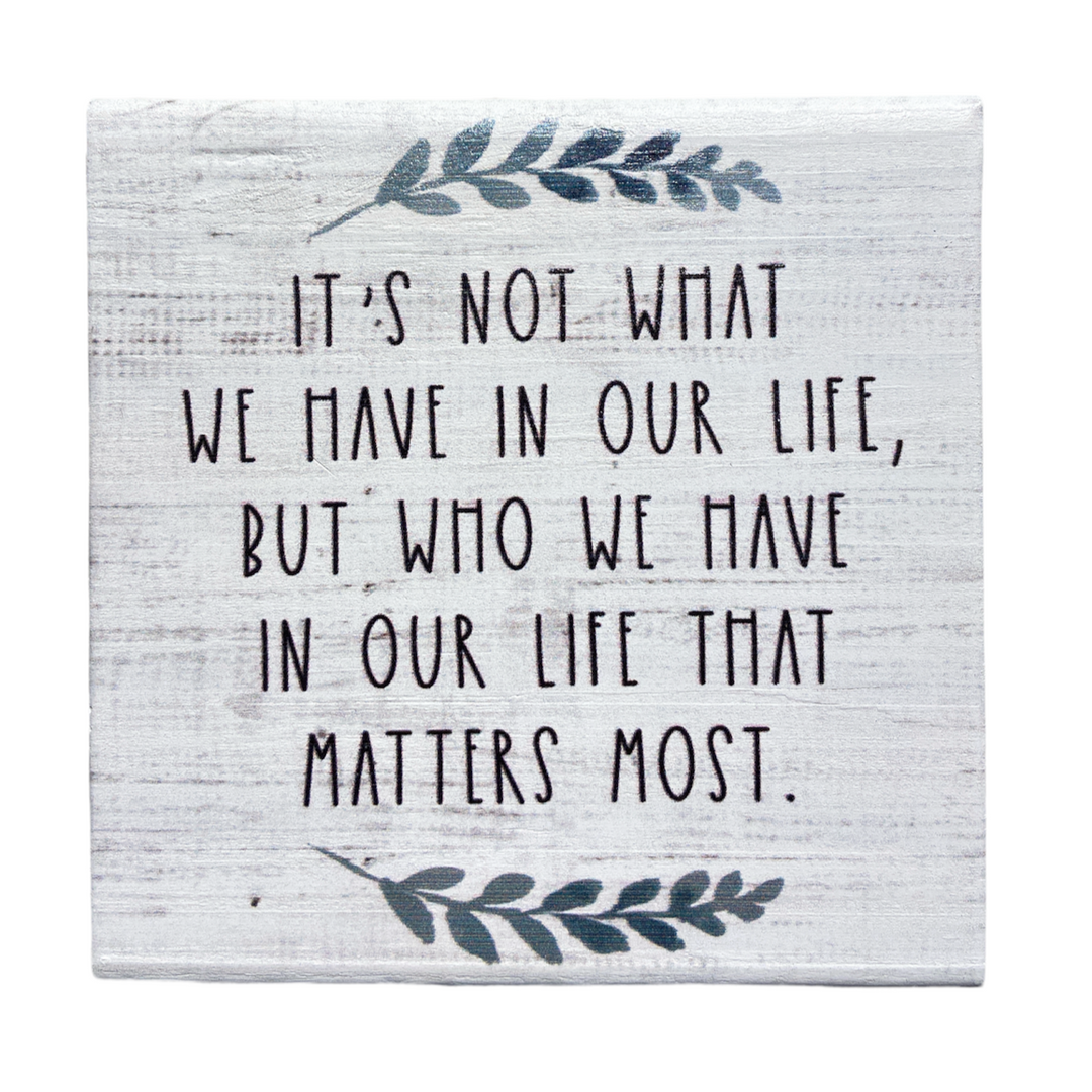 The "Who We Have" handcrafted decorative sign by SincereSurroundings showcases a rustic design featuring the quote, "It's not what we have in our life, but who we have in our life that matters most." Surrounded by simple leaf illustrations, it offers easy display to bring warmth and charm to any Rock Rapids home.