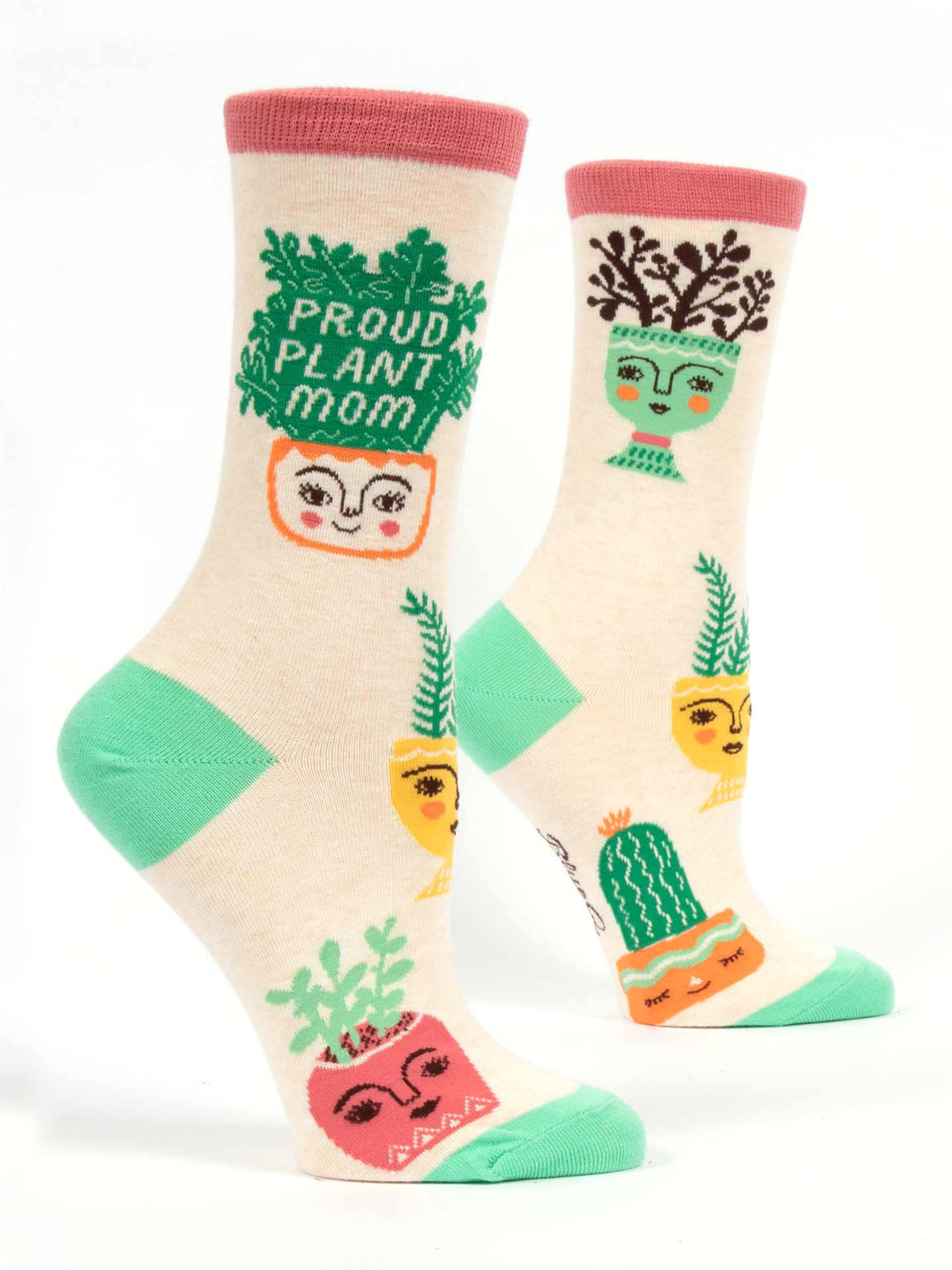 The "Proud Plant Mom" socks by Blue Q are light beige with green heels and toes, decorated with colorful plant pot illustrations featuring faces. One sock displays the text "Proud Plant Mom," while the other showcases various potted plants such as cacti and Boston Ferns. The top rim is adorned with pink details. These socks are crafted from a Nylon Cotton Spandex blend.