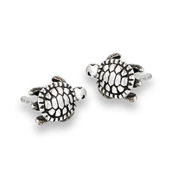 Presenting the Turtle Silver Stud earrings by Welman, a pair of small, 9 mm silver studs shaped like sea turtles. These earrings showcase detailed shell patterns and flippers that lend them a realistic appearance. Crafted with Sterling Silver Face technology to be mask-friendly, these exquisite pieces are displayed against a white background.