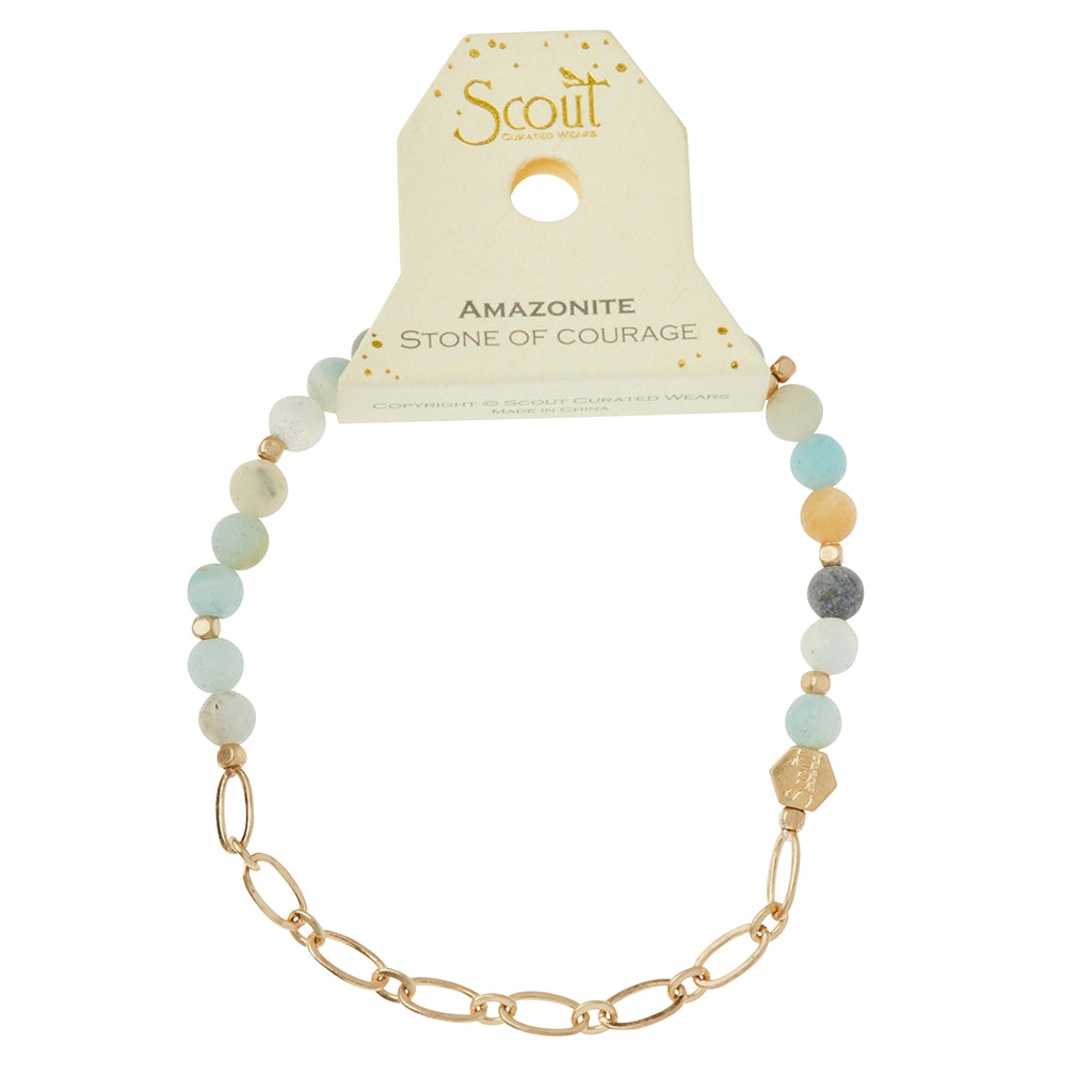 Displayed is the Chain Bracelet Amazonite/Gold, crafted with Amazonite beads in shades of blue and green, complemented by gold accents and a paperclip chain. Designed by Scout Jewelry, it is tagged with "Scout" and "Amazonite Stone of Courage," showcasing the beauty of semi-precious gemstones.